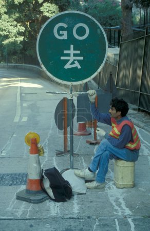 Photo for Workers controll a road at a construction site on a road in Central in the city of Hongkong in the city of Hongkong in Hongkong.  China, Hongkong, May, 1999 - Royalty Free Image