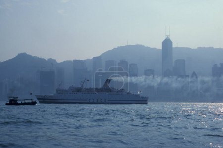 Téléchargez les photos : Un navire cosco avec vue sur le port de Victoria en face de la Skyline du centre de Hongkong du point de vue de Kowloon dans la ville de Hongkong à Hongkong. Chine, Hongkong, mai 1999 - en image libre de droit