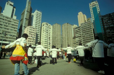 Téléchargez les photos : Peuple exercice et Tai chi en face de la Skyline de Hongkong centrale dans la ville de Hongkong à Hongkong. Chine, Hongkong, mai 1997 - en image libre de droit