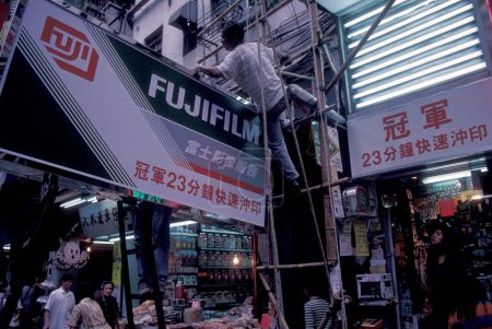 Foto de Trabajadores en el trabajo en una película de Fuji advetising en la ciudad de Hong Kong en Hong Kong. China, Hong Kong, mayo de 1999 - Imagen libre de derechos