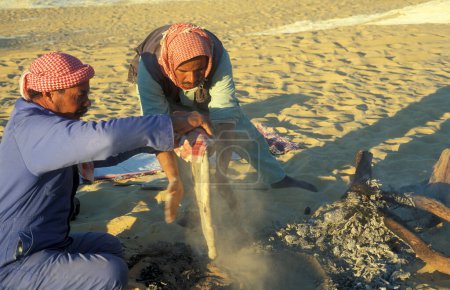 Foto de Hombres beduinos están horneando pan en la arena en un tour turístico en el desierto blanco cerca de la aldea de Farafra en el desierto libio u occidental de Egipto en el norte de África, Egipto, Farafra, marzo de 2000 - Imagen libre de derechos