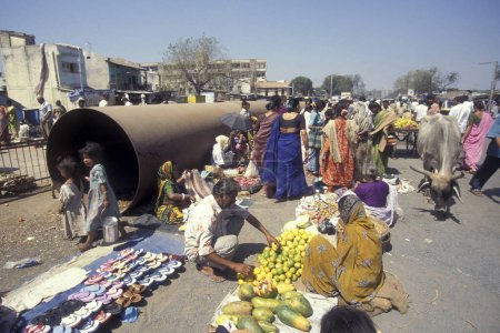 Téléchargez les photos : Personnes devant un grand tuyau d'eau au marché alimentaire dans la ville de Surat dans la province du Gujarat en Inde. Inde, Gujarat, avril 1998 - en image libre de droit