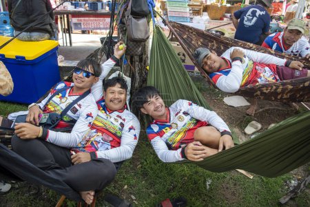 Photo for Members of Dragonboat or Longboat team relax in a Hammock on the Lake Khao Tao at the Longboat race of Hua Hin on the Lake Khao Tao reservoir south of City of Hua Hin.  Thailand, Hua Hin, December, 2023 - Royalty Free Image