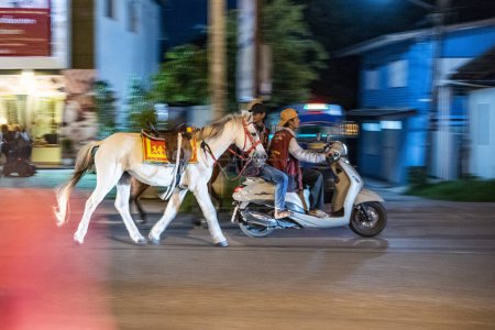 Téléchargez les photos : Guides à cheval avec moto sont après le travail sur le chemin du retour de Khao Takiab à la ville de Hua Hin dans la province de Prachuap Khiri Khan en Thaïlande, Thaïlande, Hua Hin, Décembre, 2023 - en image libre de droit