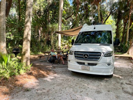 Téléchargez les photos : Mount Dora, FL États-Unis - 30 mars 2023 : Un homme assis à côté d'un van dans un camping à Trimble Park à Mount Dora, Floride. - en image libre de droit