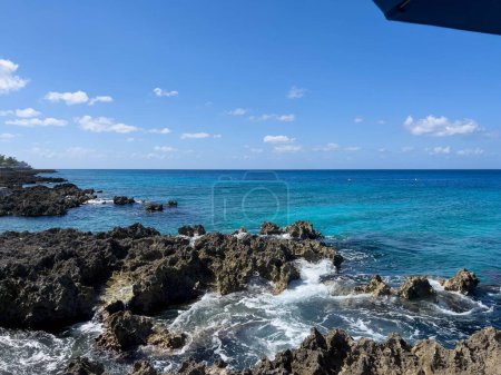 The clear turquoise blue ocean off of turtle reef in Cayman Islands on a beautiful blue sky day.
