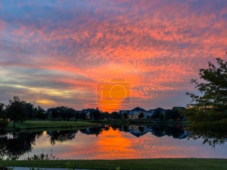 Sonnenuntergang in einer Nachbarschaft, die sich auf einem See im Laureate Park Lake Nona Orlando, Florida, USA spiegelt.