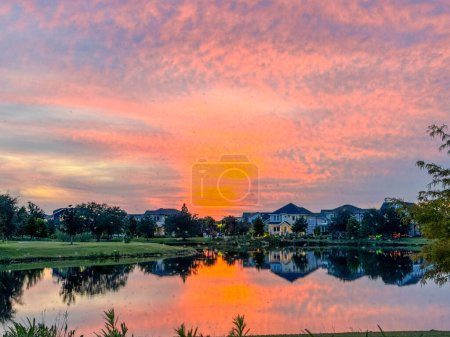 Sonnenuntergang in einer Nachbarschaft, die sich auf einem See im Laureate Park Lake Nona Orlando, Florida, USA spiegelt.