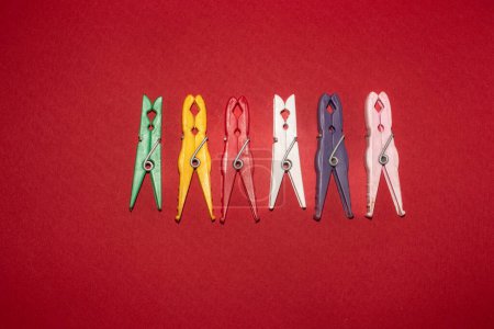 Multicolored plastic clothespins on a red background. Different colors