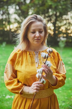 Téléchargez les photos : Belle femme ukrainienne dans une robe brodée tient un brin de coton - en image libre de droit