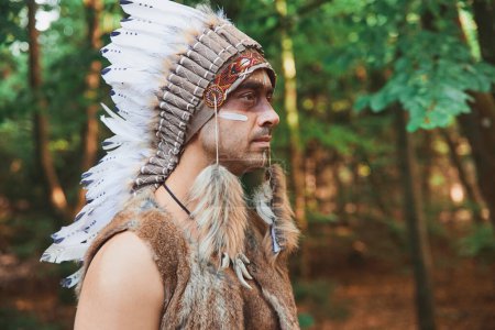 Téléchargez les photos : A man in traditional Native American clothing in the evening forest. - en image libre de droit