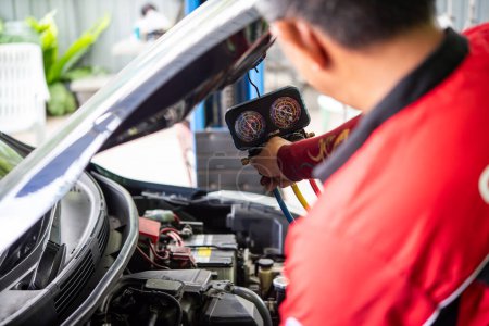 Photo for Bangkok, Thailand - May 4, 2023 : Unidentified car mechanic or serviceman refilling air condition and checking a air compressor for fix and repair problem at car garage or repair shop - Royalty Free Image