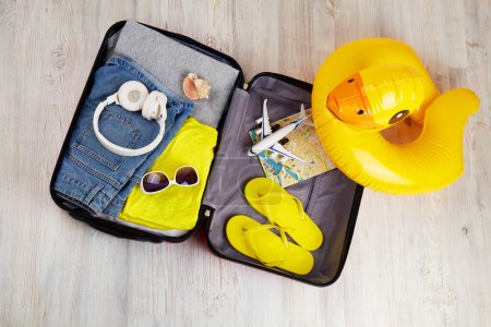 Téléchargez les photos : Valise avec vêtements et accessoires de loisirs. Voyage d'été, préparation pour le voyage. Vue du dessus. - en image libre de droit