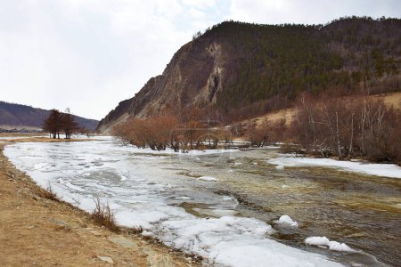 Buguldeika River near a high mountain in spring, the process of melting ice. Spring landscape