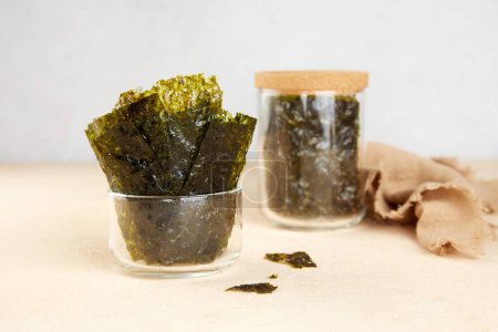 Algues nori croustillantes dans des bocaux en verre sur fond gris. Feuilles traditionnelles japonaises d'algues sèches. Une collation saine