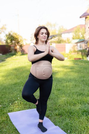 Photo for Pregnancy woman breathing and calm with yoga outdoor, doing stretching exercise on grass. Self Care, Yoga, Pregnant, Maternity Concept. Enjoy motherhood, health care, hobbies. - Royalty Free Image