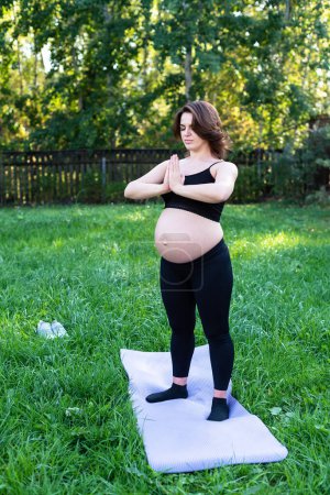 Photo for Pregnancy woman breathing and calm with yoga outdoor, doing stretching exercise on grass. Self Care, Yoga, Pregnant, Maternity Concept. Enjoy motherhood, health care, hobbies. - Royalty Free Image