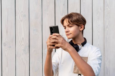 Photo for Teen boy taking selfie on a white wooden background outdoor, sharing in social media, teen lifestyle, blogging, teenager self-admiration, Self obsession. - Royalty Free Image