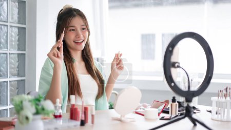 Photo for Beauty blogger concept, Young woman show concealer to introducing product and record video for Vlog. - Royalty Free Image