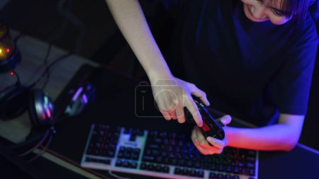 Téléchargez les photos : Femme cyber hacker gamer jouer ou diffuser des jeux vidéo sur ordinateur avec joystick dans la lumière au néon. - en image libre de droit