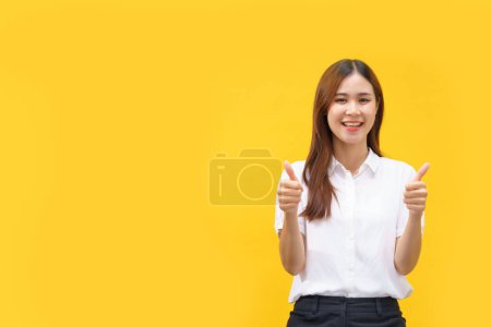 Téléchargez les photos : Les femmes font le pouce vers le haut geste avec les deux mains tandis que le bonheur souriant sur fond jaune isolé. - en image libre de droit