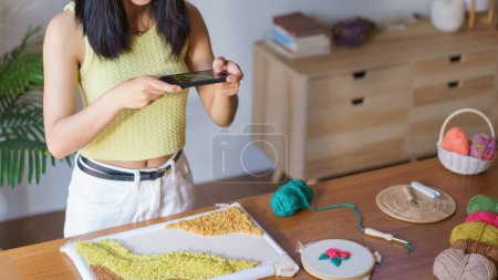 Photo for Needlework concept, Women use phone taking photo of embroidery fabric punch frame diy performance. - Royalty Free Image