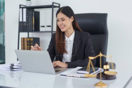 Lawyer woman reading business contract and checking legal agreement on laptop in legal office.