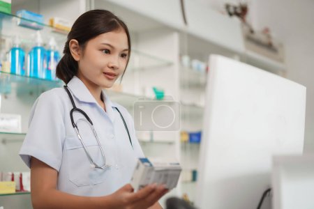 Medicine and health concept, Female pharmacist hold medicine product to working with cash register.