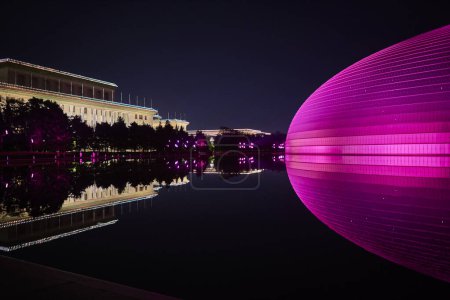 Nachtaufnahme des National Centre for the Performing Arts NCPA mit dem Nationalen Volkskongress (Große Halle des Volkes) im Hintergrund in Peking, China am 20. April 2024