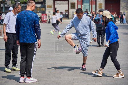 Foto de Personas que practican Jianzi, deporte nacional tradicional chino en el que los jugadores están pateando lanzadera en el aire en Beijing, China, el 21 de abril de 2024 - Imagen libre de derechos