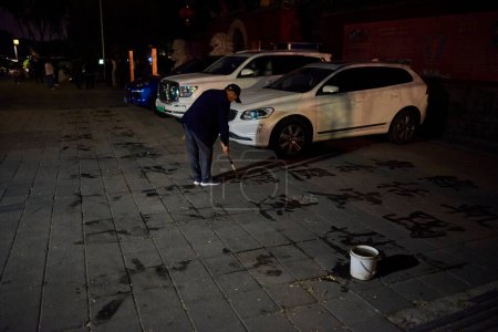 Man practicing water calligraphy (ground writing - dishu), popular pastime among retired Chinese, in Beijing, China on 18 April 2024