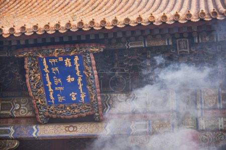 Téléchargez les photos : Panneau d'entrée du temple Yonghe du bouddhisme tibétain avec fumée d'encens, dans le district de Dongcheng à Pékin, en Chine, le 21 avril 2024 - en image libre de droit