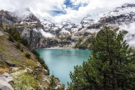 The view of Oeschinenee Lake and Oeschinen valley amongst Bernese Alps mountain tops. Famous tourist attraction in Switzerland