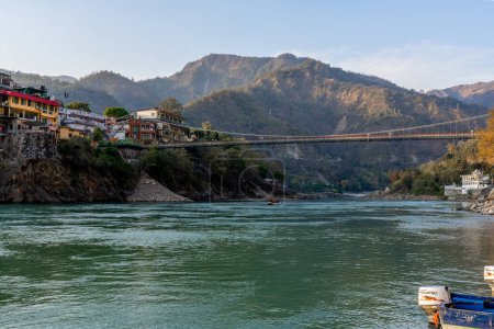 Téléchargez les photos : Rishikesh, Uttarakhand, Inde - 28.03.2023 : Belle rivière Ganga à Rishikesh avec pont entouré de ashrames et de temples. Eau pure et propre de la rivière. Photo de haute qualité - en image libre de droit