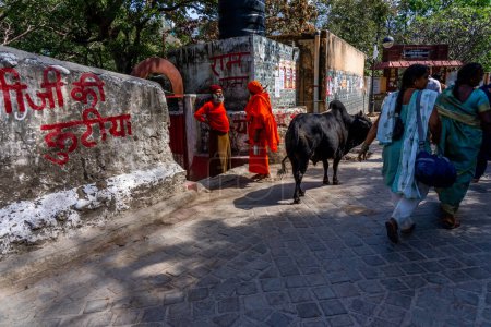 Téléchargez les photos : Rishikesh,Uttarakhand - 29.03.2023. Les gens en vêtements de siddha orange traditionnels marchent dans les rues de Rishikesh, ville sainte indienne. Photo de haute qualité - en image libre de droit