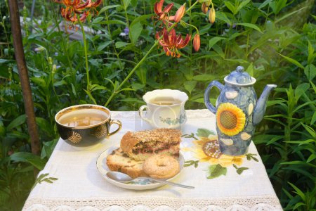 Photo for Mint tea outdoors in mugs, cookies and cupcakes in a plate, lilia flowers - Royalty Free Image
