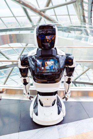 Téléchargez les photos : Promobot robofoto portrait pleine longueur avec l'image des personnes exposées dans l'intérieur technologique moderne. Visage souriant du robot. Promobot androïde blanc. Astana Nur-Sultan, Kazakhstan - 10.24.2022 - en image libre de droit