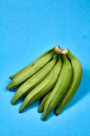 Foto de Plátano verde fresco sobre fondo azul, maqueno, barraganete, dominico. cuchillo de mesa manos - Imagen libre de derechos