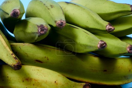 Foto de Plátano verde fresco sobre fondo azul, maqueno, barraganete, dominico. cuchillo de mesa manos - Imagen libre de derechos