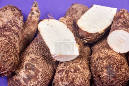 closeup of taro root vegetable, eddo malanga, hands table slice