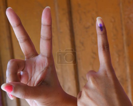 Tinta en el dedo post casting voto en indio con signo de victoria.