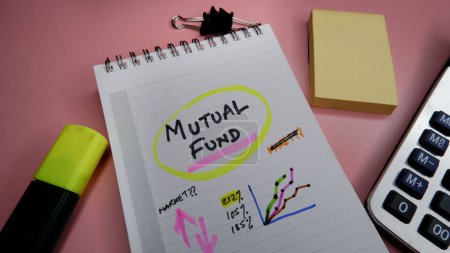 Concept of mutual fund written on note pad while doing planning for investment with graphs.