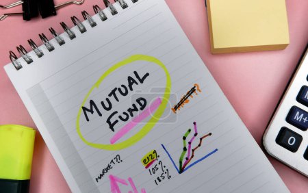 Concept of mutual fund written on note pad while doing planning for investment with graphs.