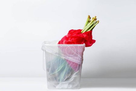 Téléchargez les photos : Fleur flétrie. Tulipes fanées dans un emballage rouge. Dans le seau à ordures. Inversé vers le bas - en image libre de droit