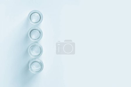 Téléchargez les photos : Ensemble de petits pots vides en verre bleu sur un fond bleu. Vue d'en haut. - en image libre de droit