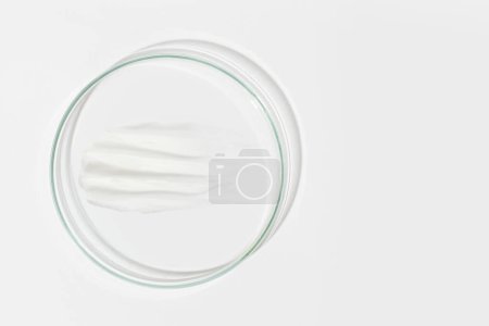 Photo for Petri dish on a light background. With a smear of white cream. Cosmetic cream, face mask, cream texture. View from above - Royalty Free Image