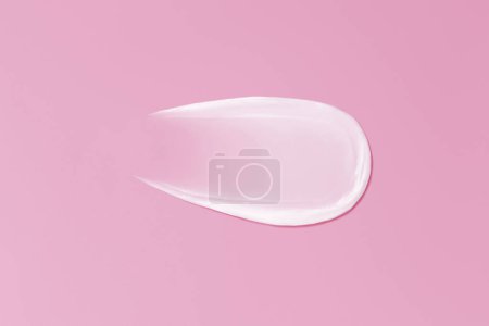 Close-up smear of cream texture on a pink background