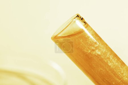Photo for Test tube with liquid gold. Glitter, varnish, liquid. Sequins. Laboratory research of cosmetics and liquids. current gold. - Royalty Free Image