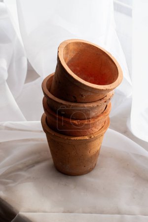 Untreated clay pots. Orange color. Autumn mood. Against the background of a delicate white curtain. Daylight. Natural color.