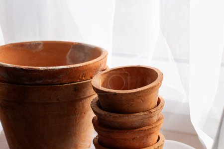 Untreated clay pots. Orange color. Autumn mood. Against the background of a delicate white curtain. Daylight. Natural color.